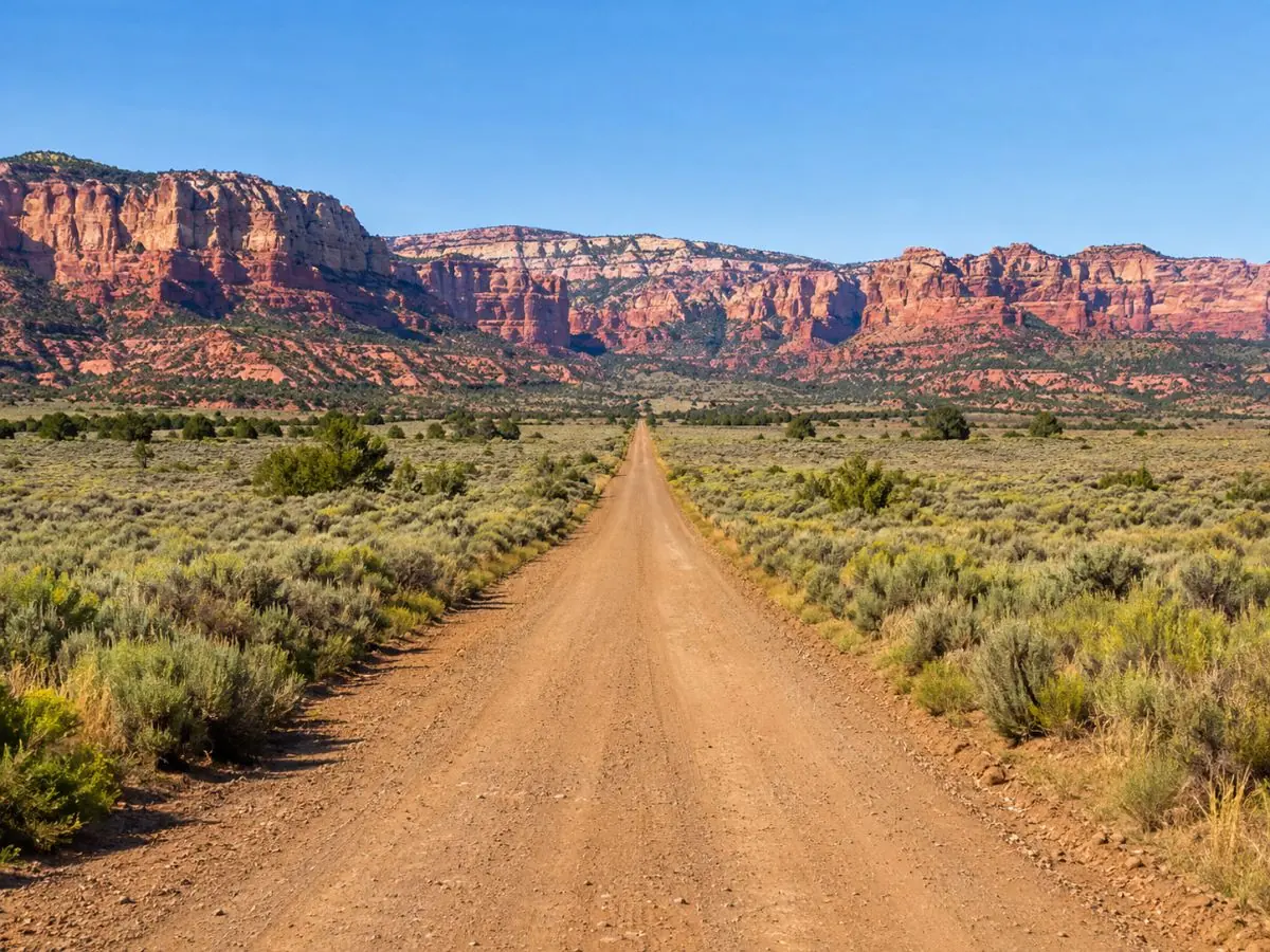 House Rock Valley Road che corre dritta tra l'artemisia verso scogliere rosa e rosse