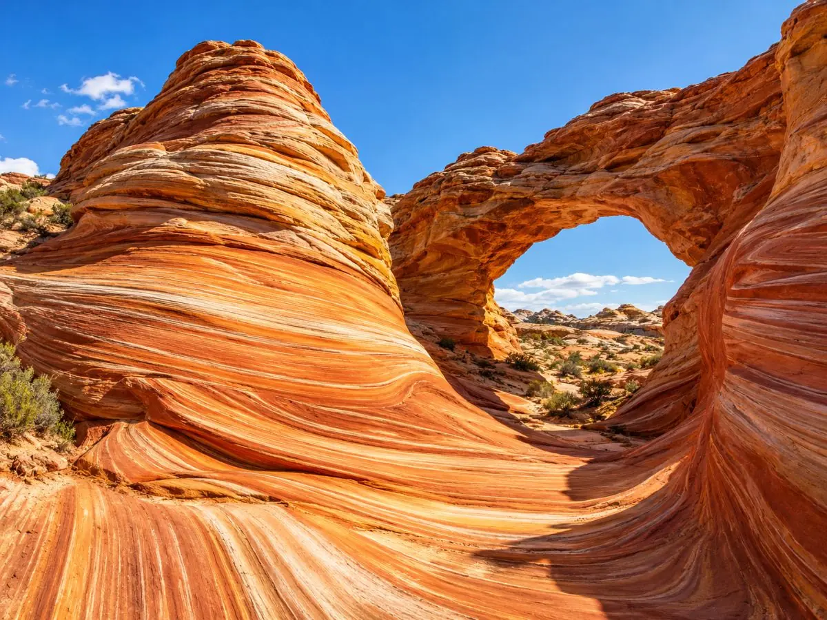 Cupole di arenaria striata arancione e un piccolo arco naturale in Coyote Buttes